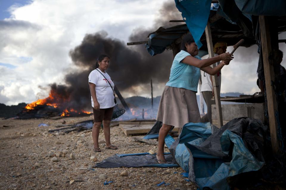 Women try to rescue some belongings after authorities blew up their illegal mining operation in Huepetuhe district in Peru's Madre de Dios region in Peru, Monday, April 28, 2014. Authorities began enforcing a ban on illegal mining Monday in the Huepetuhe district. They had given the state’s illegal miners until April 19 to get legal or halt operations. Illegal mining accounts for about 20 percent of Peru's gold exports, but most miners are poor migrants from the Andean highlands. (AP Photo/Rodrigo Abd)