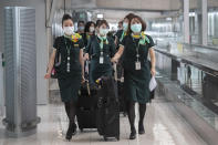 Flight crew wear protective masks as they arrive at the Suvarnabhumi Airport in Bangkok, Friday, July 3, 2020. As the country starts to ease its travel restrictions allowing foreign visitors in on a controlled basis, a laboratory at the airport will have the results of COVID-19 virus testing ready within 90 minutes for arriving travelers. (AP Photo/Sakchai Lalit)