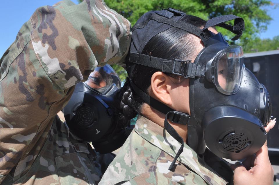 U.S. Air Force Staff Sgt. Debra McGrew, a structures specialist in the 908th Civil Engineer Squadron, left, assists Senior Airman Helena Urban, also 908 CES, with her donning her gas mask during an annual training event May 1, 2023, at Maxwell Air Force Base, Alabama.
