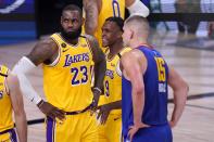 Los Angeles Lakers' LeBron James (23), Rajon Rondo (9) and Denver Nuggets' Nikola Jokic, wait for play to restart during the second half an NBA conference final playoff basketball game, Friday, Sept. 18, 2020, in Lake Buena Vista, Fla. (AP Photo/Mark J. Terrill)