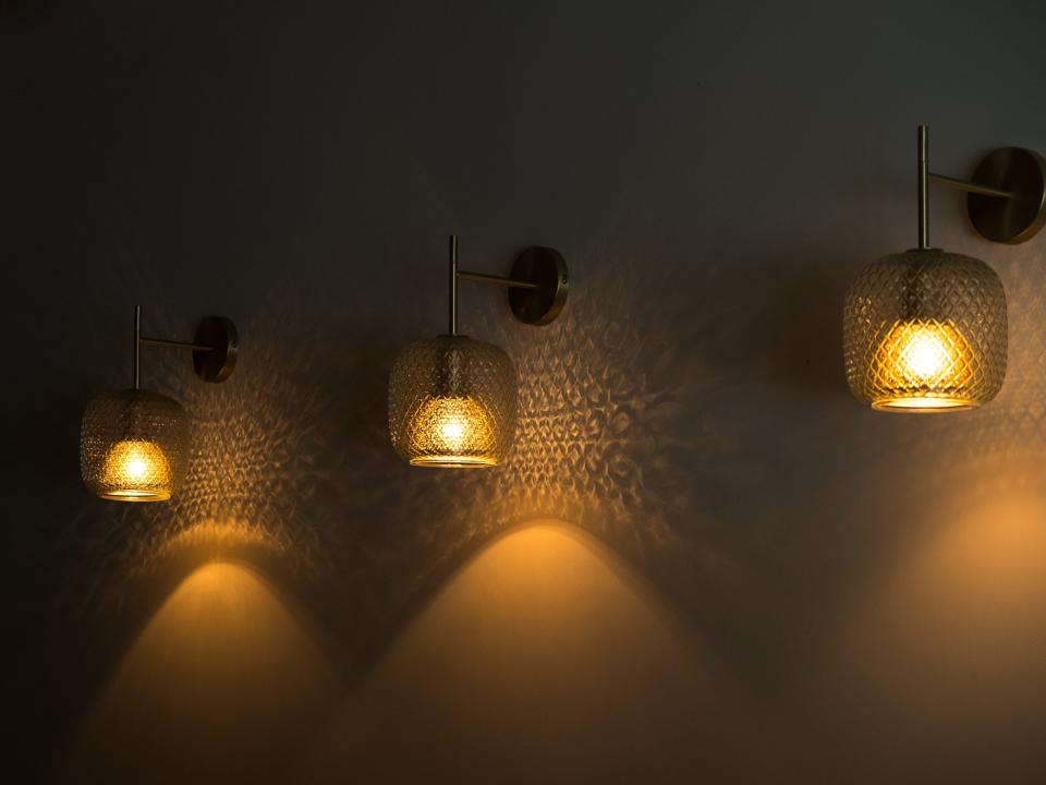 Three patterned crystal sconces emit yellow light in dimly light room