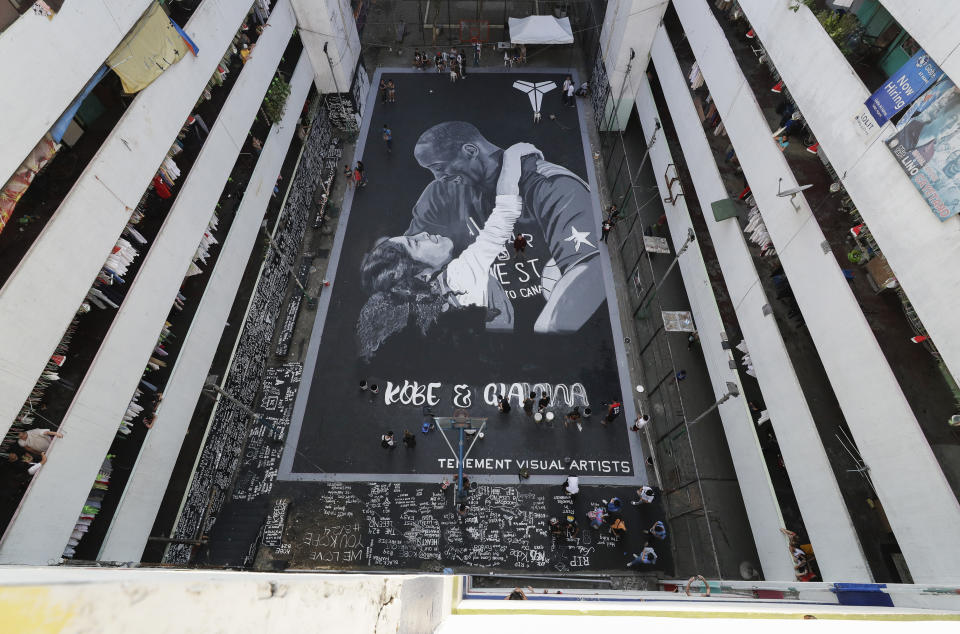 FILE - Artists put the finishing touches on a giant mural of former NBA basketball player Kobe Bryant and daughter Gianna at a basketball court in Taguig, south of Manila, Philippines on Tuesday, Jan. 28, 2020. Considering 110 million people live in the Philippines, it’s not feasible that they all would be basketball fans. “But it’s close,” said Tim Cone, the country’s winningest coach. He might not be wrong. The island nation has basketball courts everywhere, an incredible passion for the NBA and now gets to showcase Manila as the centerpiece of the Basketball World Cup. (AP Photo/Aaron Favila, File)