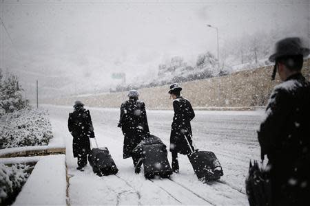 Ultra-Orthodox Jewish men walk on a snow-covered road in winter in Jerusalem December 12, 2013. REUTERS/Amir Cohen