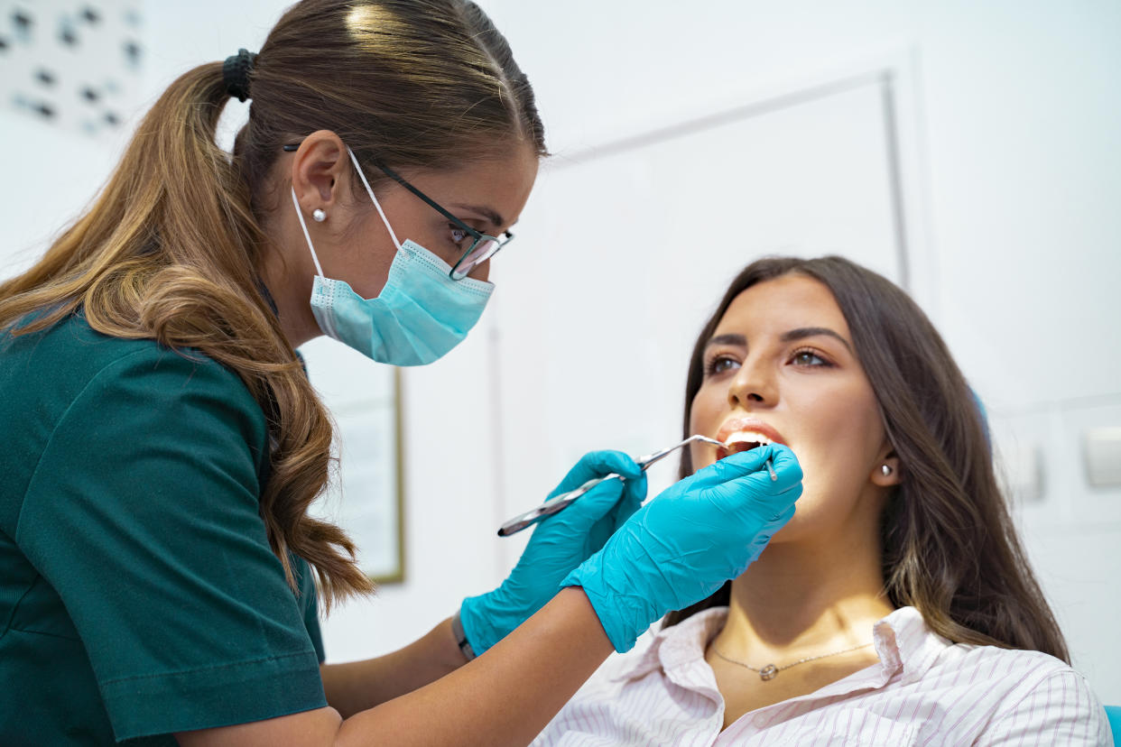 Closeup shot professional dentist with protective surgical mask, doing check up of patient