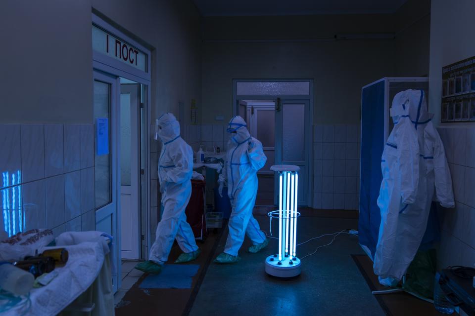 In this photo taken on Monday, May 4, 2020, medical specialists, wearing special suits to protect against coronavirus, walk through a disinfectant corridor toward intensive care unit at a regional hospital in Chernivtsi, Ukraine. Ukraine's troubled health care system has been overwhelmed by COVID-19, even though it has reported a relatively low number of cases. (AP Photo/Evgeniy Maloletka)