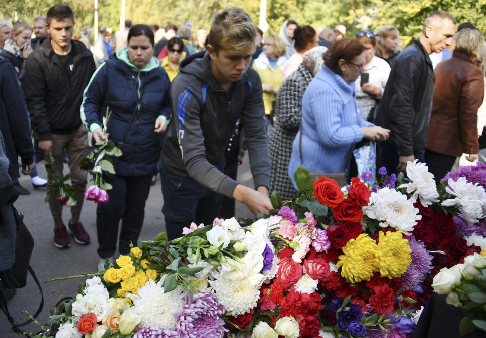 People lay flowers to commemorate the victims of the attack on a vocational college, in Kerch, Crimea, Thursday, Oct. 18, 2018. Authorities on the Crimean Peninsula were searching for a possible accomplice of the student who carried out a shooting and bomb attack on a vocational school Wednesday, killing 20 people and wounding more than 50 others, an official said Thursday. (AP Photo/Sergei Demidov)