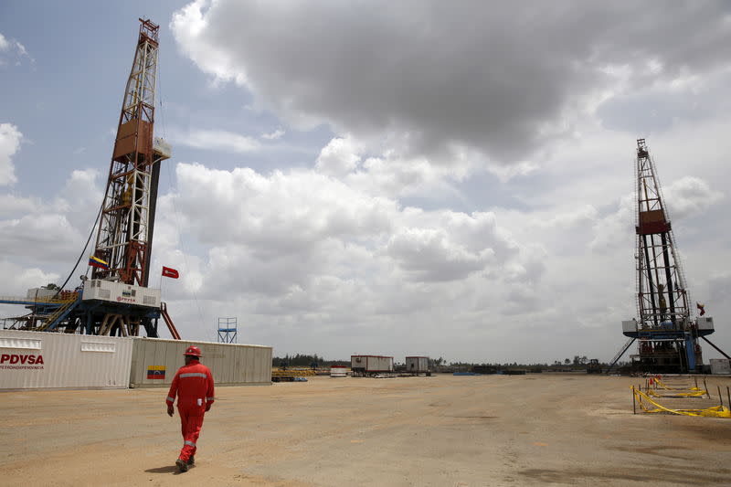 An oilfield worker walks next to drilling rigs at an oil well operated by Venezuela's state oil company PDVSA, in the oil rich Orinoco belt, near Morichal at the state of Monagas April 16, 2015. REUTERS/Carlos Garcia Rawlins