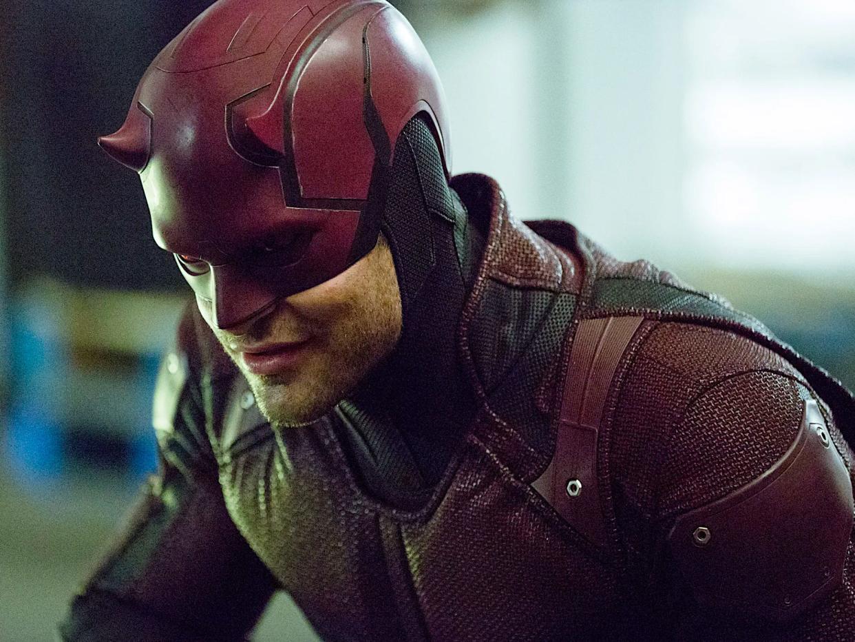 A man in a red and black costume with a mask that has horns on it.