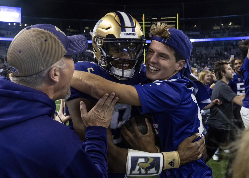 Fans celebrate with Washington quarterback Michael Penix Jr., center, after an NCAA college football game against Michigan State, Saturday, Sept. 17, 2022, in Seattle. (AP Photo/Stephen Brashear)