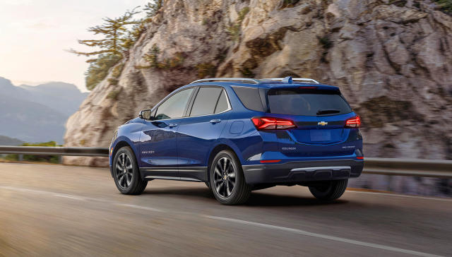 The 2022 Chevrolet Equinox Premier in blue driving along a cliffside highway with a rocky outcrop in the background.