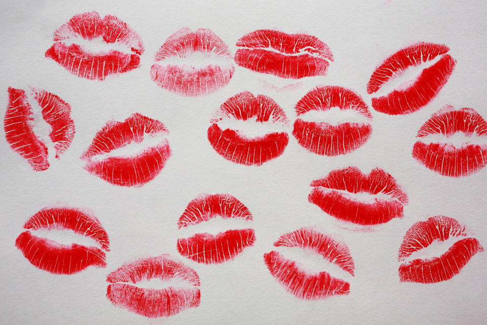 Multiple red lipstick lip prints arranged in a scattered pattern on a white background