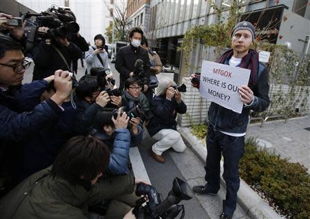 Kolin Burges (R), a self-styled cryptocurrency trader and former software engineer from London, holds a placard to protest against Mt. Gox, as photographers take photos of him in front of the building where the digital marketplace operator was formerly housed in Tokyo February 26, 2014. REUTERS/Toru Hanai