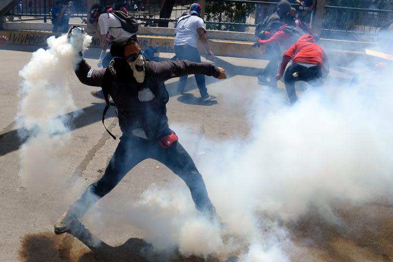 An anti-government activist resturns tear gas to members of the National Police during a protest against Venezuelan President Nicolas Maduro, in Caracas, on March 20, 2014