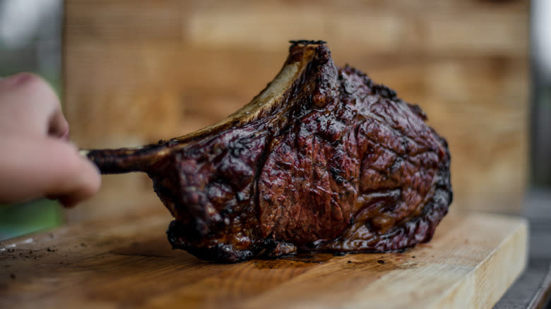 cook holding ribeye by bone