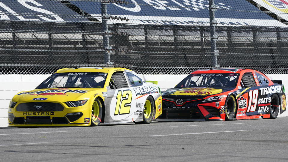 Ryan Blaney (12) and Martin Truex Jr. (19) approach the third turn during a NASCAR Cup Series auto race at Martinsville Speedway in Martinsville, Va., Sunday, April 11, 2021. (AP Photo/Steve Helber)