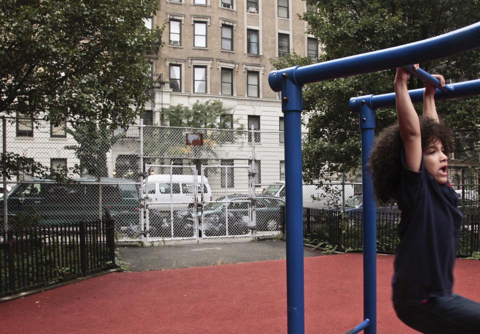 Nicholas Gayles, 6, a student at P.S. 75, plays in the school's playground across the street from a shelter on 95th Street on Wednesday, Oct. 3, 2012 in New York. Neighborhood residents are in turmoil, saying they were blindsided by the suddenness of the shelter's opening, sharing the same block as the school. (AP Photo/Bebeto Matthews)