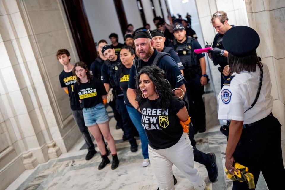 A woman with her hands tied screams as she is led in front of a group of others