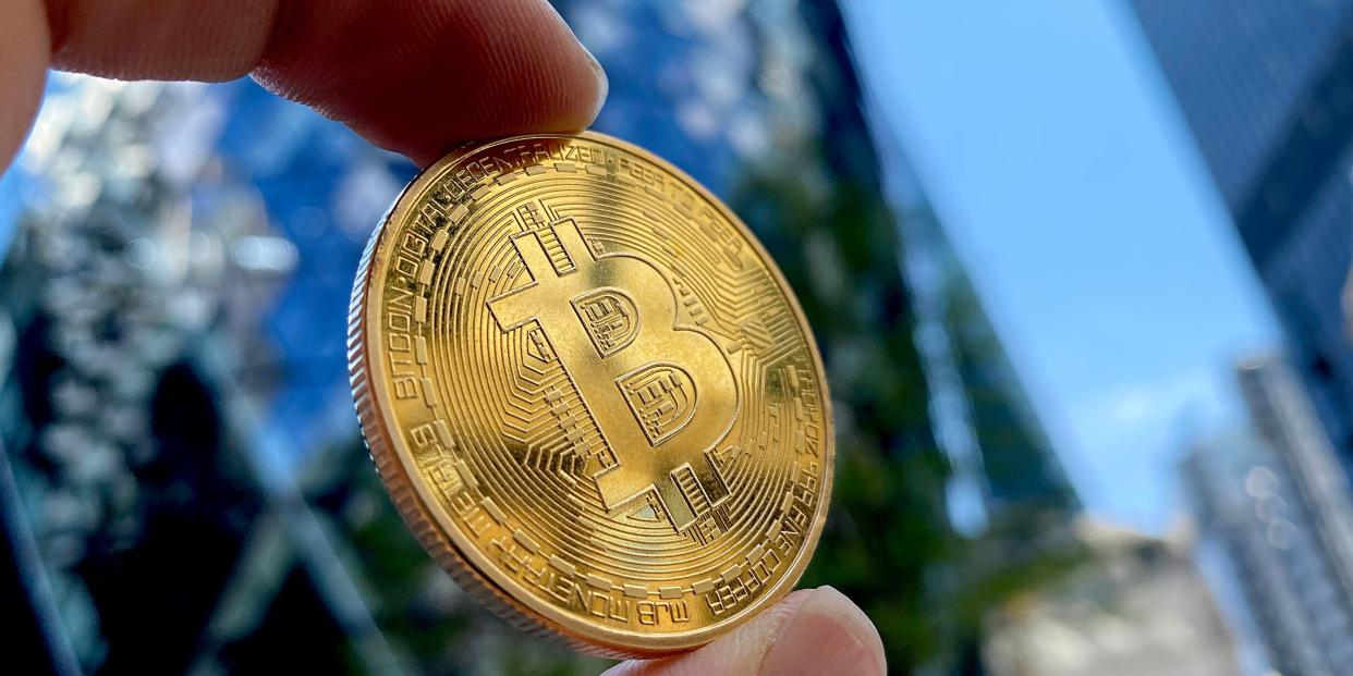 A hand holds a bitcoin toward the sky in this photo representation of the cryptocurrency.