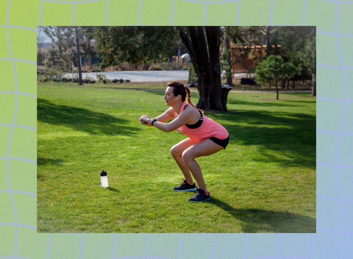 middle-aged woman in pink tank top and black shorts doing squats in park on sunny day