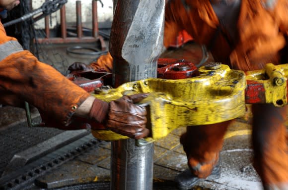 Rig workers fitting a pipe.