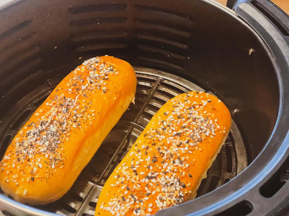 two hot dog buns in an air fryer basket