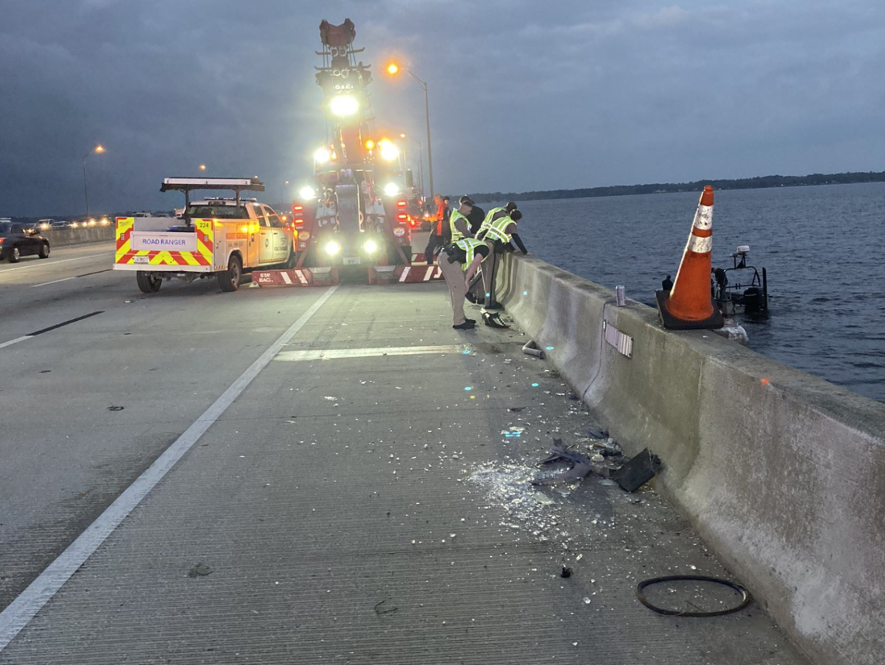 Crews try to get to a submerged car toppled over the Buckman Bridge after being hit by a Road Ranger truck early Feb. 28, 2023,, in Jacksonville.