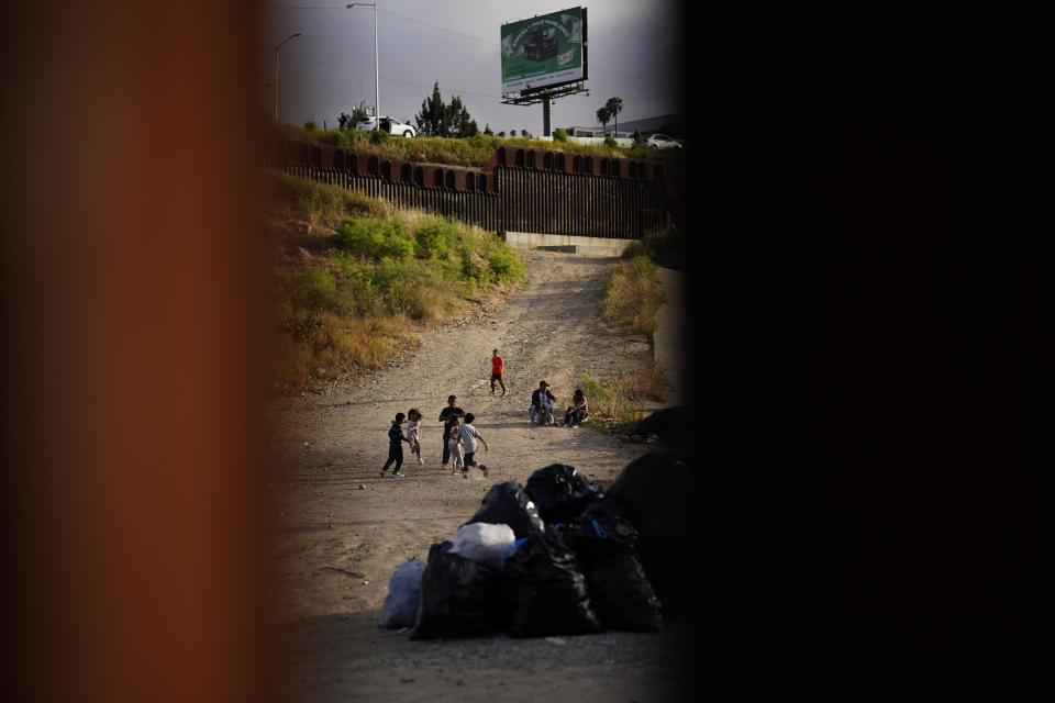 Niños juegan fútbol con una botella de agua vacía mientras aguardan a solicitar asilo entre dos muros fronterizos el jueves 11 de mayo de 2023, en San Diego. Muchos de los cientos de migrantes que están entre los muros que separan a Tijuana, México, de San Diego han estado esperando durante días para solicitar asilo. Las restricciones estadounidenses al asilo, implementadas por la pandemia de COVID-19 y conocidas como Título 42, expiraron el 11 de mayo. (AP Foto/Gregory Bull)