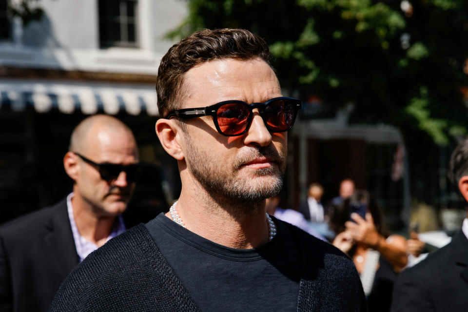 Justin Timberlake wearing sunglasses, preparing to speak to reporters.