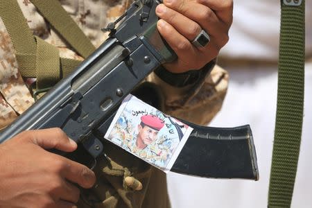 A soldier holds a rifle with a photo of Major-General Abdel-Rab al-Shadadi, a top general in forces loyal to Yemeni President Abd-Rabbu Mansour Hadi's government killed in fighting with Iran-aligned Houthi troops, during his funeral in Marib city, Yemen October 9, 2016. REUTERS/Ali Owidha