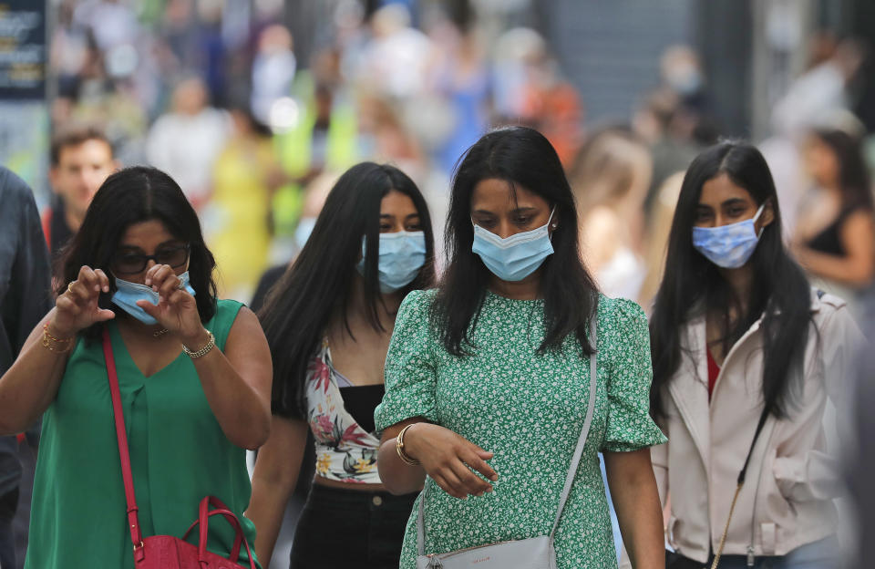 Shoppers wear face coverings to protect themselves from COVID-19 as they walk along Oxford Street in London, Friday, July 24, 2020. New rules on wearing masks in England have come into force, with people going to shops, banks and supermarkets now required to wear face coverings. Police can hand out fines of 100 pounds ($127) if people refuse, but authorities are hoping that peer pressure will prompt compliance. (AP Photo/Frank Augstein)