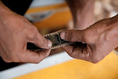 A worker re-connects a broken film strip before a wedding party in Bogor, Indonesia, February 18, 2017. REUTERS/Beawiharta/Files