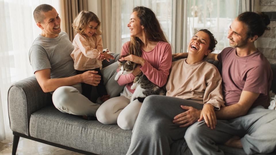 People laughing on couch with cat