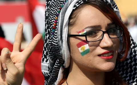 A woman flashes the V-sign as Iraqi Kurds take part in a rally to urge people to vote in the upcoming independence referendum - Credit: SAFIN HAMED/AFP/Getty Images