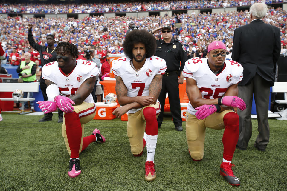 Colin Kaepernick kneels during the national anthem last season, alongside two of his teammates, Eli Harold (left) and Eric Reid (right). (Getty Images)