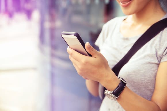 Young woman smiling as she looks at a smartphone