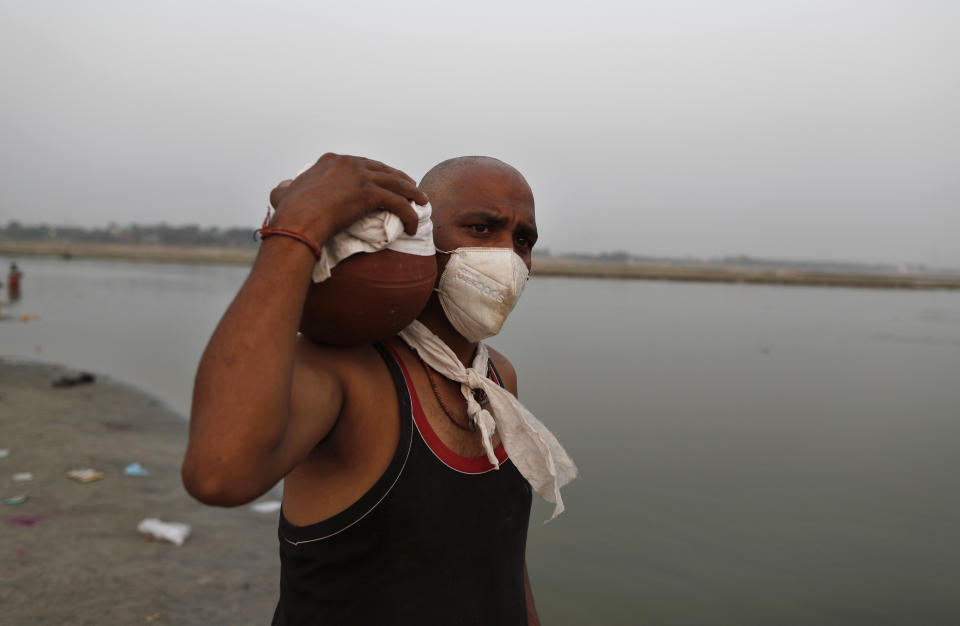 Family member of a COVID-19 victim carries the urn containing the ashes for immersion to perform last rites at Sangam, the confluence of rivers Ganges and Yamuna in Prayagraj, India, Saturday, May 1, 2021. India on Saturday set yet another daily global record with 401,993 new cases, taking its tally to more than 19.1 million. Another 3,523 people died in the past 24 hours, raising the overall fatalities to 211,853, according to the Health Ministry. Experts believe both figures are an undercount. (AP Photo/Rajesh Kumar Singh)