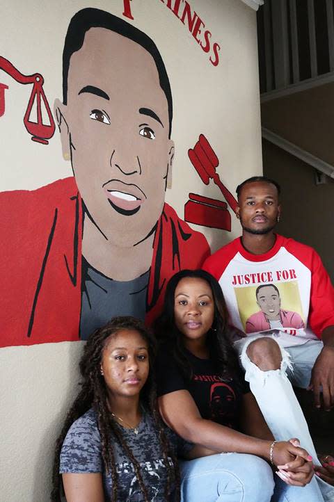 Charmaine Lawson with her daughter Chloe, left, and son Anthony, right, beneath a mural of Josiah in their home in Perris, California. (Photo by Terrell Tangonan)