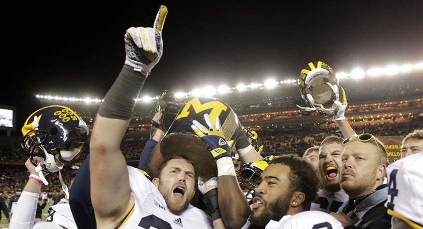 Michigan players hoist the Little Brown Jug after an NCAA college football game against Minnesota, Saturday, Oct. 31, 2015 in Minneapolis.