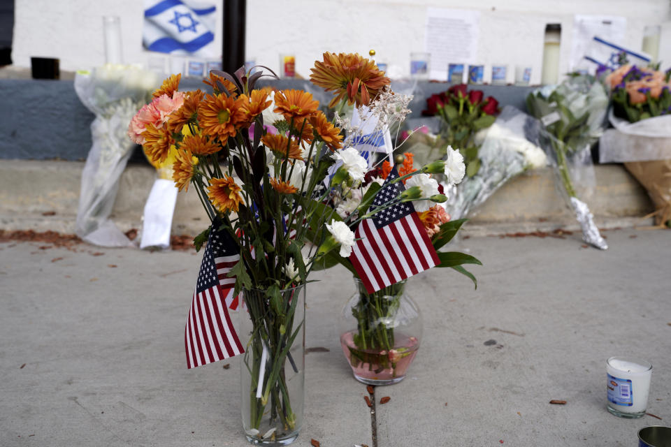 Flowers and flags are left at a makeshift shrine placed at the scene of a Sunday confrontation that lead to death of a demonstrator Tuesday, Nov. 7, 2023, in Thousand Oaks, Calif. Paul Kessler, 69, died at a hospital on Monday from a head injury after witnesses reported he was involved in a "physical altercation" during pro-Israel and pro-Palestinian demonstrations at an intersection in Thousand Oaks, a suburb northwest of Los Angeles, authorities said. (AP Photo/Richard Vogel)