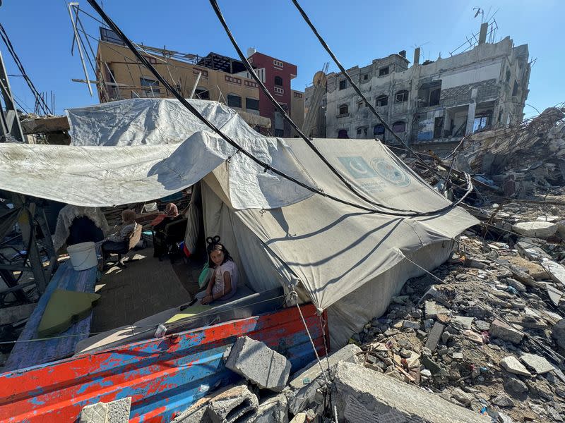 A displaced Palestinian girl, who fled her house due to Israel's military offensive, sits outside her family's tent, in Rafah, in the southern Gaza Strip