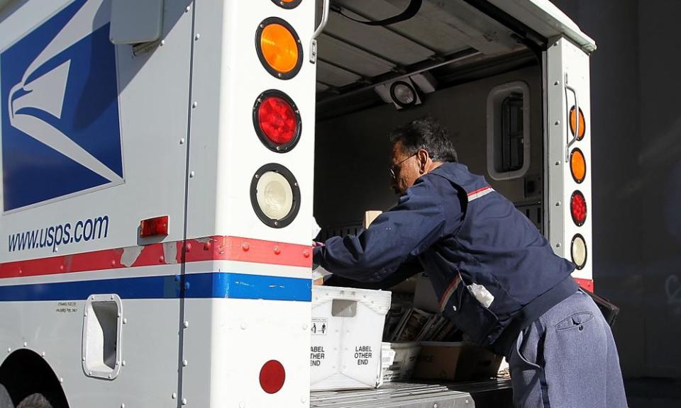 A US postal service letter carrier arranges mail in his truck. 