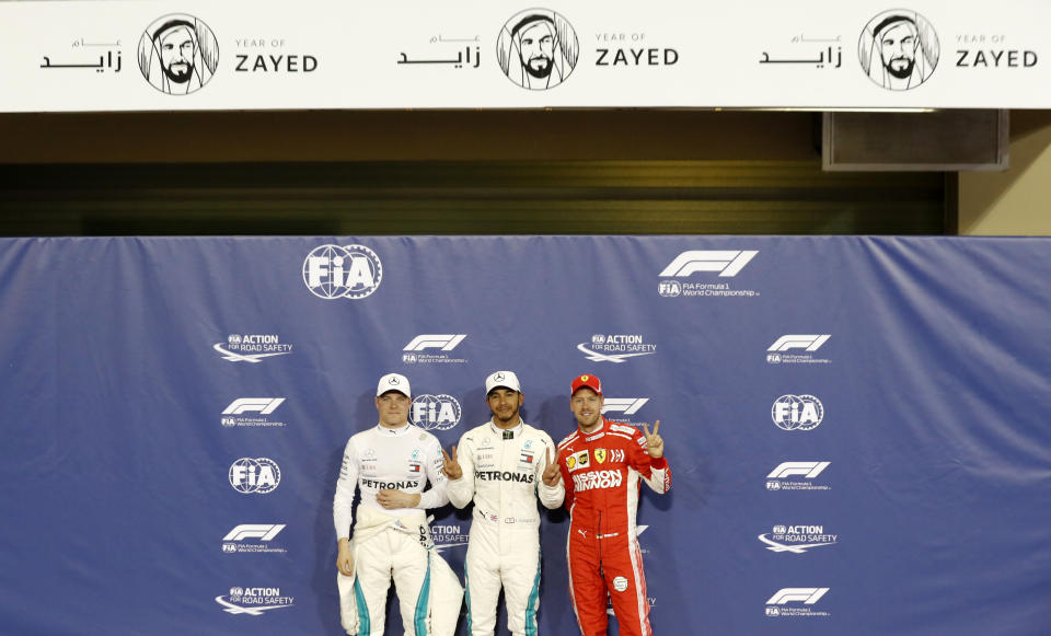 Mercedes driver Lewis Hamilton of Britain, center, who earned pole position, Ferrari driver Sebastian Vettel of Germany, right, who came in third and Mercedes driver Valtteri Bottas of Finland, left, who earned the second best time, posing for photos after the qualifying session for the Emirates Formula One Grand Prix at the Yas Marina racetrack in Abu Dhabi, United Arab Emirates, Saturday, Nov. 24, 2018. The Emirates Formula One Grand Prix will take place on Sunday. (AP Photo/Hassan Ammar)