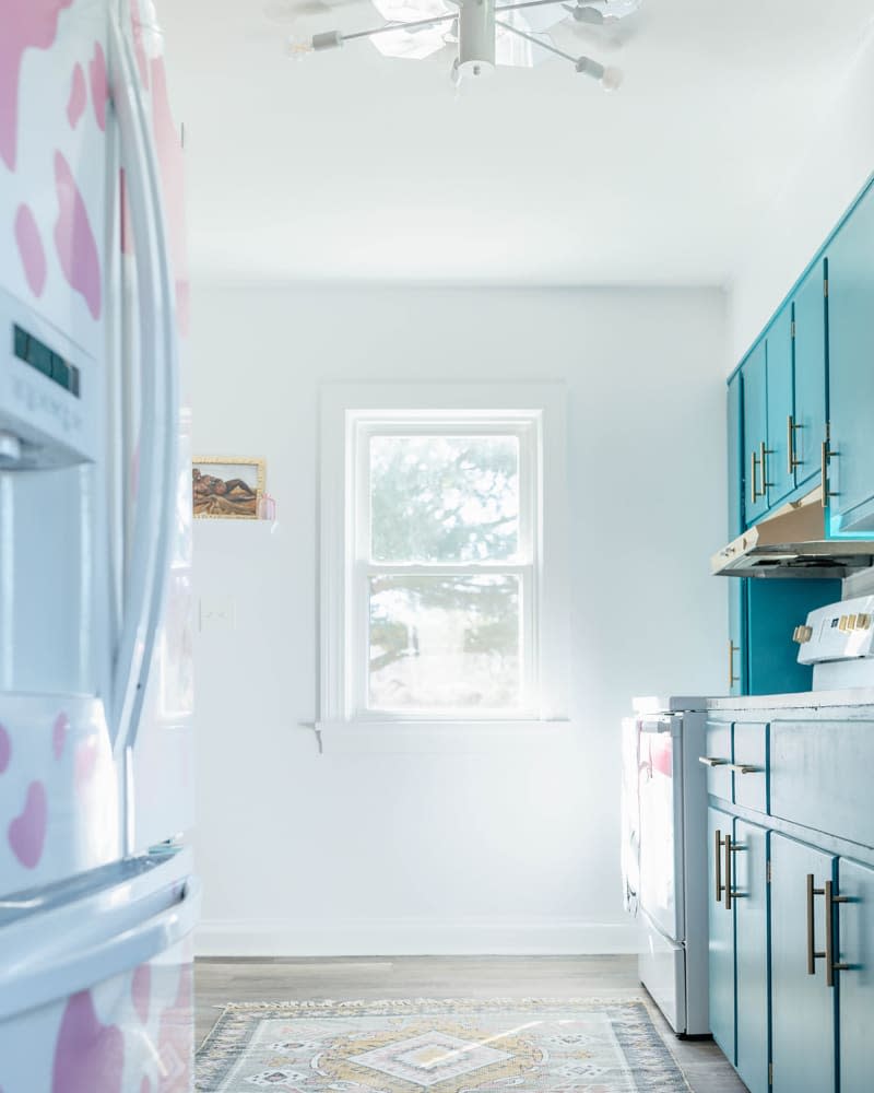 Renovated white kitchen with light turquoise cabinets and pink and white accents