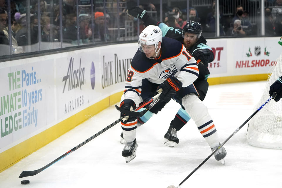 Edmonton Oilers left wing Zach Hyman (18) skates ahead of Seattle Kraken defenseman Adam Larsson (6) during the second period of an NHL hockey game Friday, Dec. 3, 2021, in Seattle. (AP Photo/Elaine Thompson)