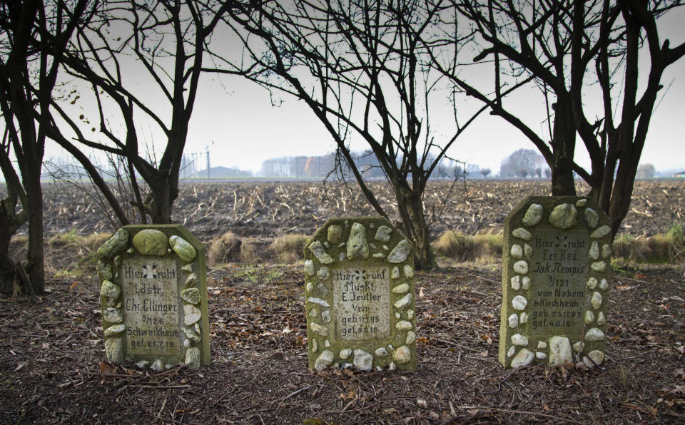 FILE - In this Thursday, Dec. 12, 2013 file photo, the fields of Flanders serve as a backdrop for the graves of three German World War I soldiers in Menen, Belgium. German Chancellor Angela Merkel will mark the 100th anniversary of the end of World War I on French soil, and President Frank-Walter Steinmeier will be in London’s Westminster Abbey for a ceremony with the queen. But in Germany, there are no national commemorations planned for the centenary of the Nov. 11 armistice that brought an end to the bloody conflict that killed more than 2 million of its troops and left 4 million wounded. That’s because the armistice did not bring peace to Germany. (AP Photo/Virginia Mayo, File)