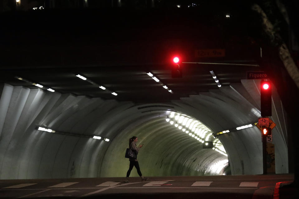 A woman walks along Figueroa Street on Wednesday, April 1, 2020, in Los Angeles. The spread of the coronavirus statewide has, so far, been slow enough to give the state time to prepare for an expected spike in cases. (AP Photo/Marcio Jose Sanchez)