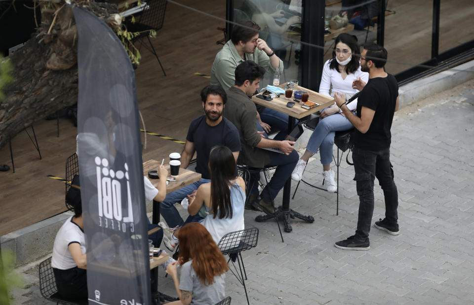 In this photo taken Saturday, June 6, 2020, people sit outside a cafe, in Ankara, Turkey. Images on social media and news agencies showed crowds picnicking and partying Saturday night without heeding to the rules of social distancing and wearing masks on the first weekend with no lockdown, prompting a reprimand from the health minister who warned that the novel coronavirus continued to pose a threat. (AP Photo/Burhan Ozbilici)