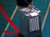 A voter casts a ballot in the lower house election at a polling station, amid the coronavirus disease (COVID-19) pandemic, in Tokyo