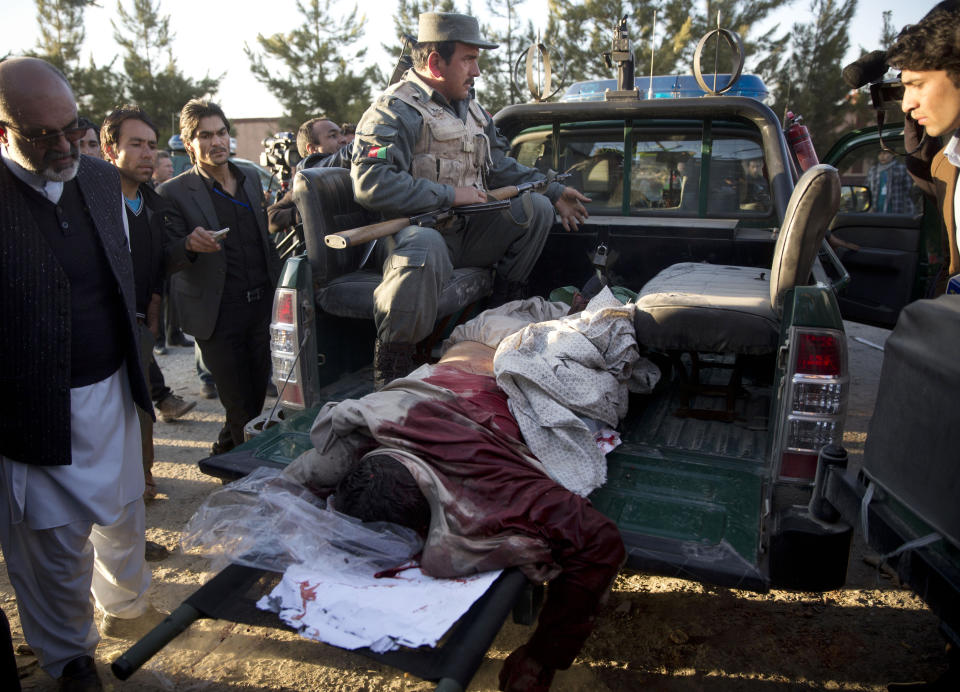 The body of an insurgent is driven away by Afghan policemen after the Taliban launched an assault with a suicide bomber detonating his vehicle outside an election office in Kabul, Afghanistan, Tuesday, March 25, 2014. Gunmen stormed into the building, trapping dozens of employees inside and killing many people. A candidate for a seat on a provincial council was among those killed, along with an election worker, a civilian and a policeman. (AP Photo/Anja Niedringhaus)