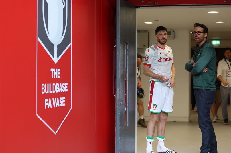 Wrexham Owner & Hollywood actor Ryan Reynolds speaks with Ben Tozer of Wrexham after the final whistle during the Buildbase FA Trophy Final between Bromley and Wrexham at Wembley Stadium on May 22, 2022 in London, England.